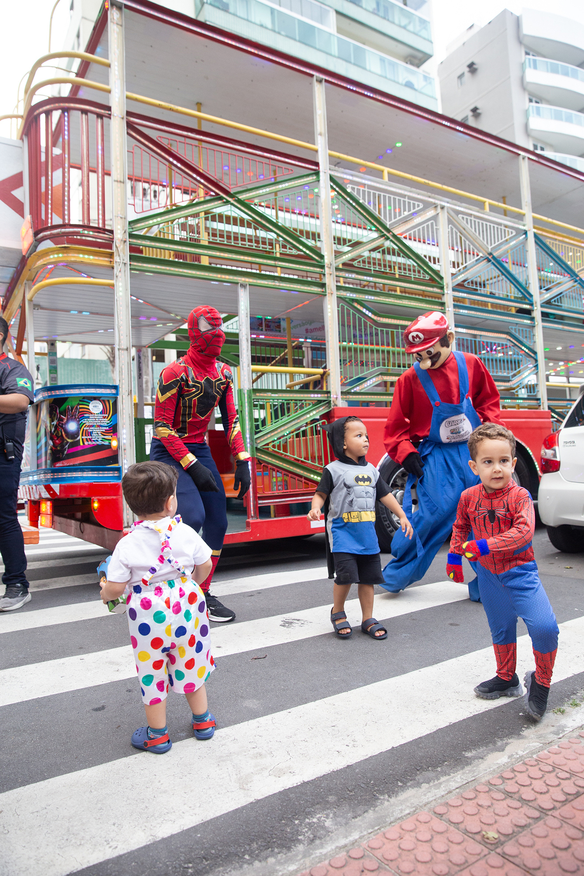 aniversariante comemorando 3 anos vestido de Homem-Aranha durante sua festa no Carretão da Alegria, dançando na calçada