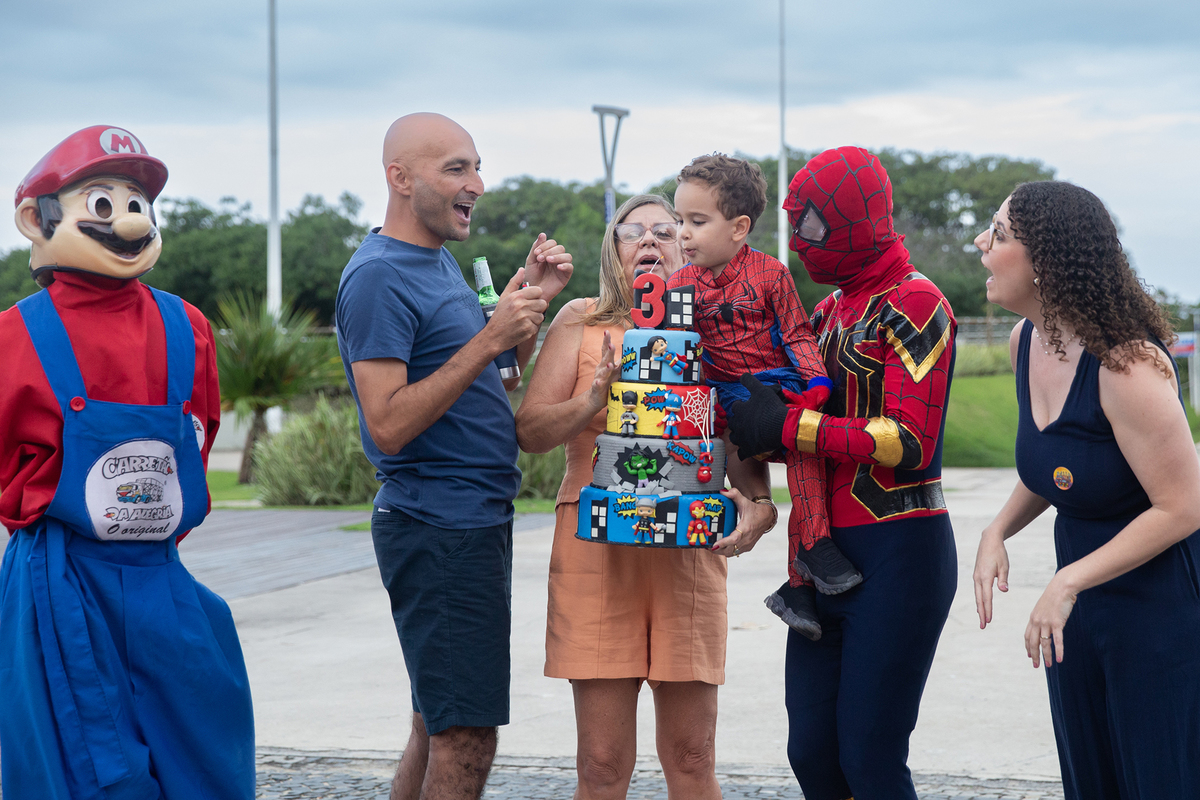 Aniversariante, junto com vovó, papai, mamãe, Homem-aranha e Mario Brós, cantando parabéns na orla de Camburi 