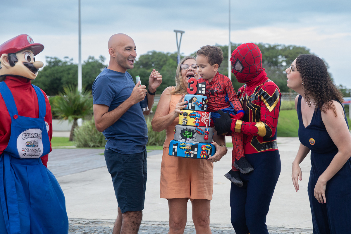 Aniversariante, junto com vovó, papai, mamãe, Homem-aranha e Mario Brós, cantando parabéns na orla de Camburi 