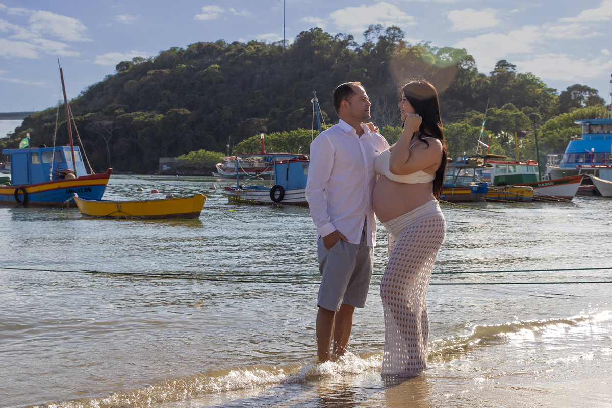 casal se olhando, na praia, com mar e terceira ponte ao fundo 