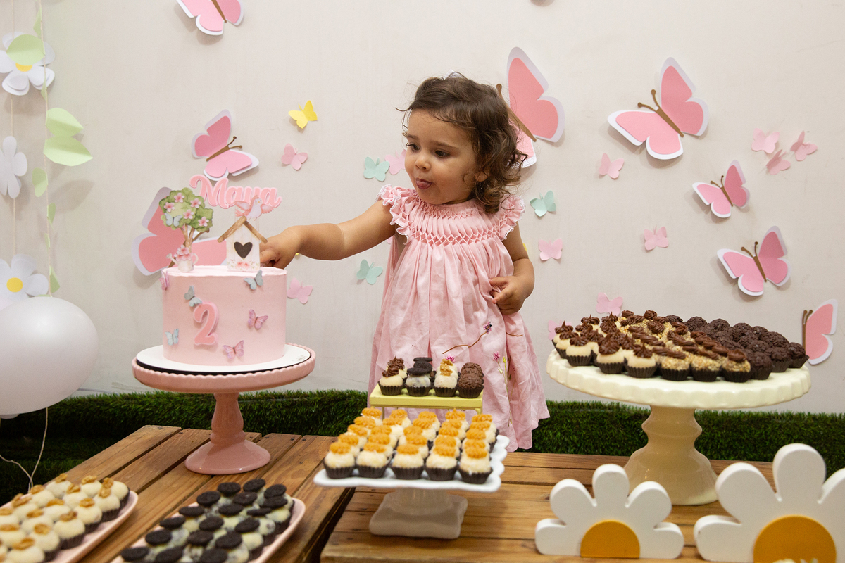 Menina comemorando 2 anos com bolo e docinhos em festa intimista em casa