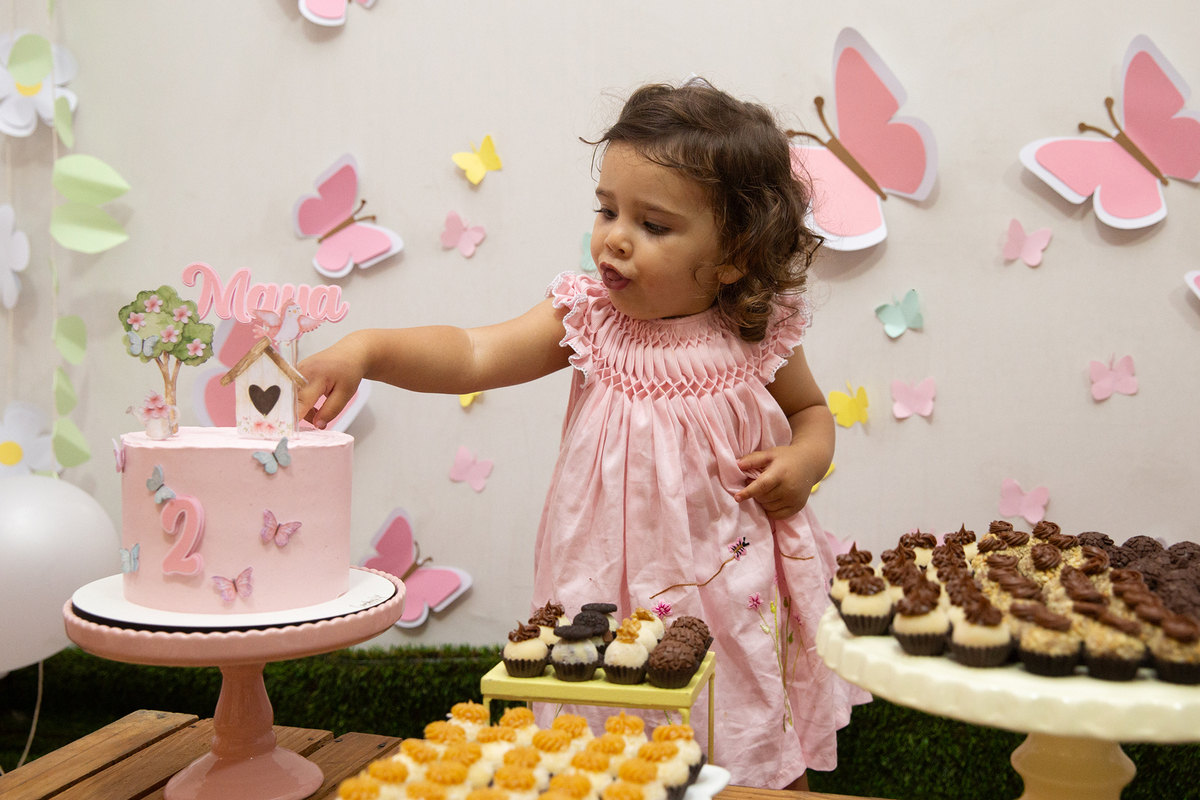 Menina comemorando 2 anos com bolo e docinhos em festa intimista em casa