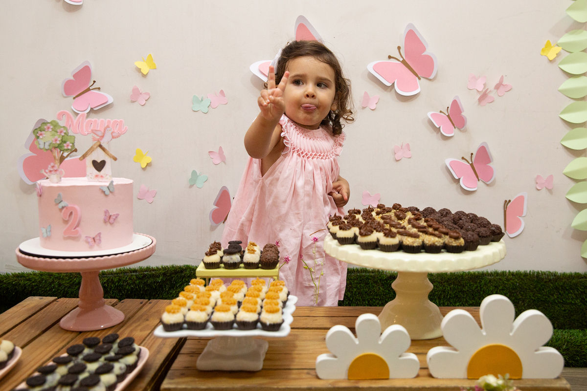 Menina comemorando 2 anos com bolo e docinhos em festa intimista em casa