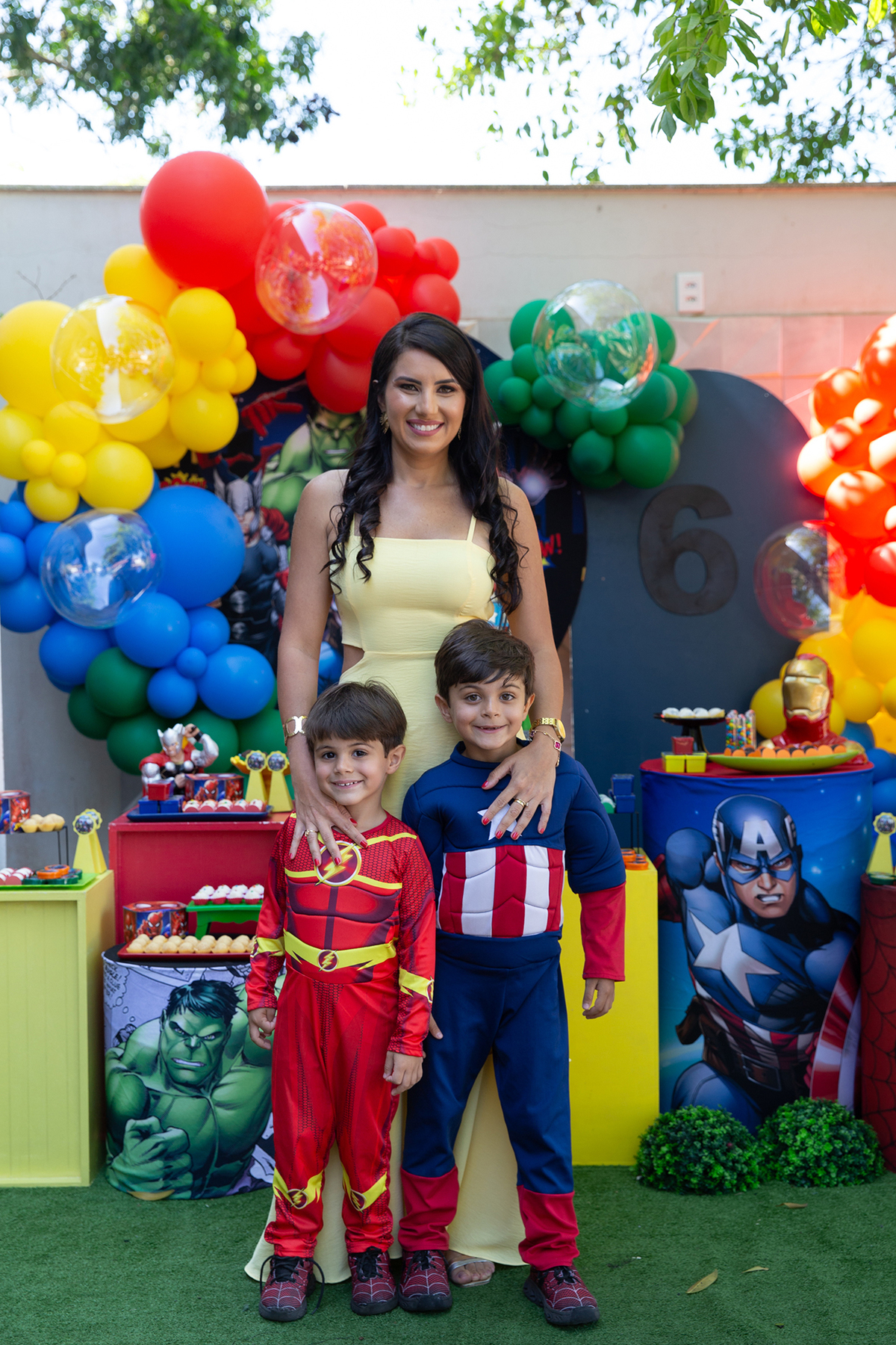 mamãe posando durante festa de aniversário com tema heróis, com o aniversariante e seu irmãozinho 