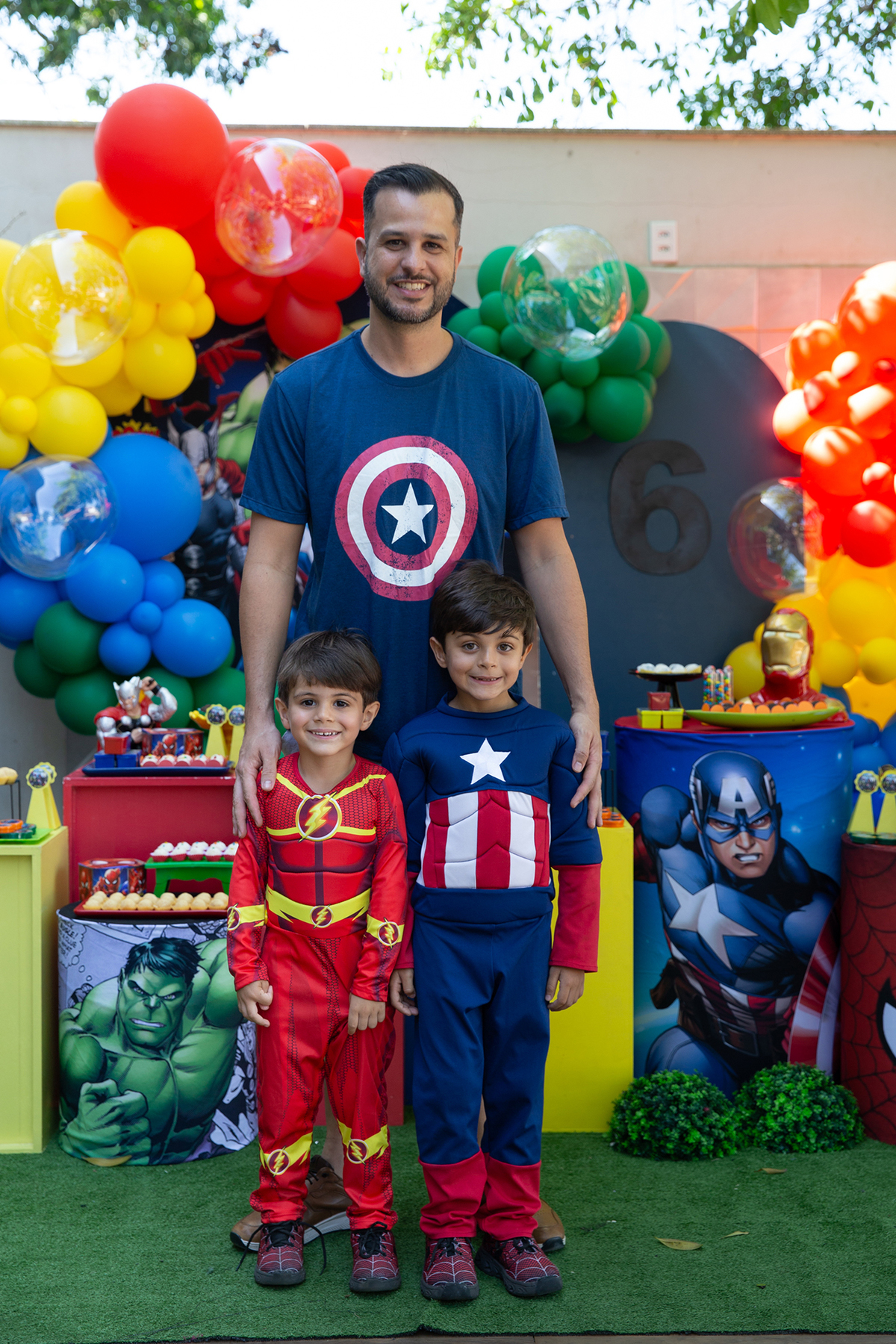 papai posando durante festa de aniversário com tema heróis, com o aniversariante e seu irmãozinho 