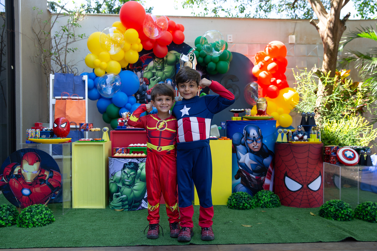 irmãos posando durante festa de aniversário com tema heróis, rodeada de amigos fantasiados