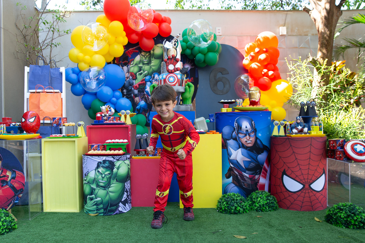 irmão de aniversariante, vestido de flash, posando em frente a decoração do aniversario 