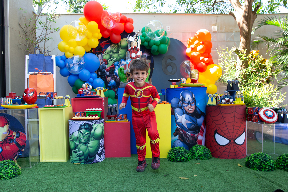 irmão de aniversariante, vestido de flash, posando em frente a decoração do aniversario 