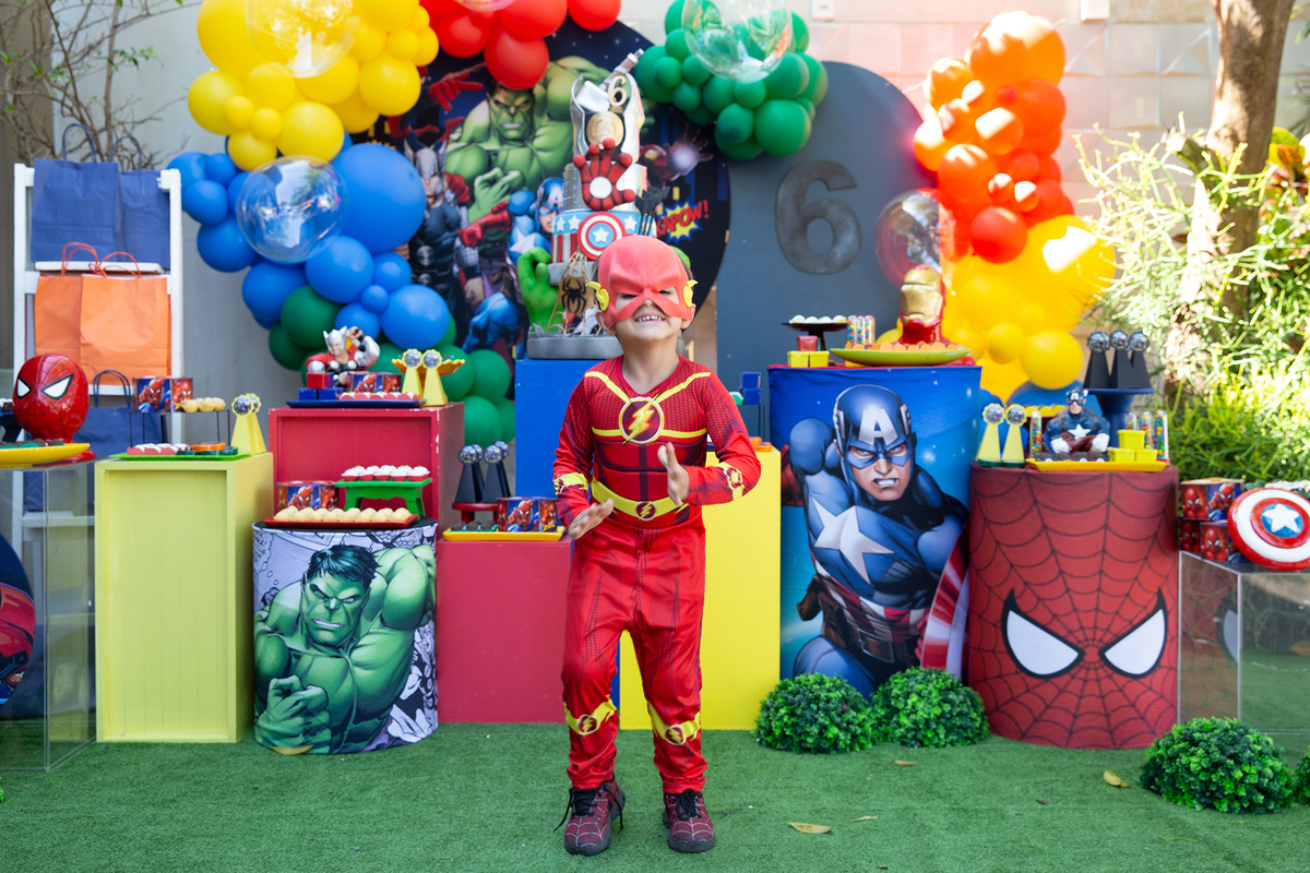 irmão de aniversariante, vestido de flash, posando em frente a decoração do aniversario 