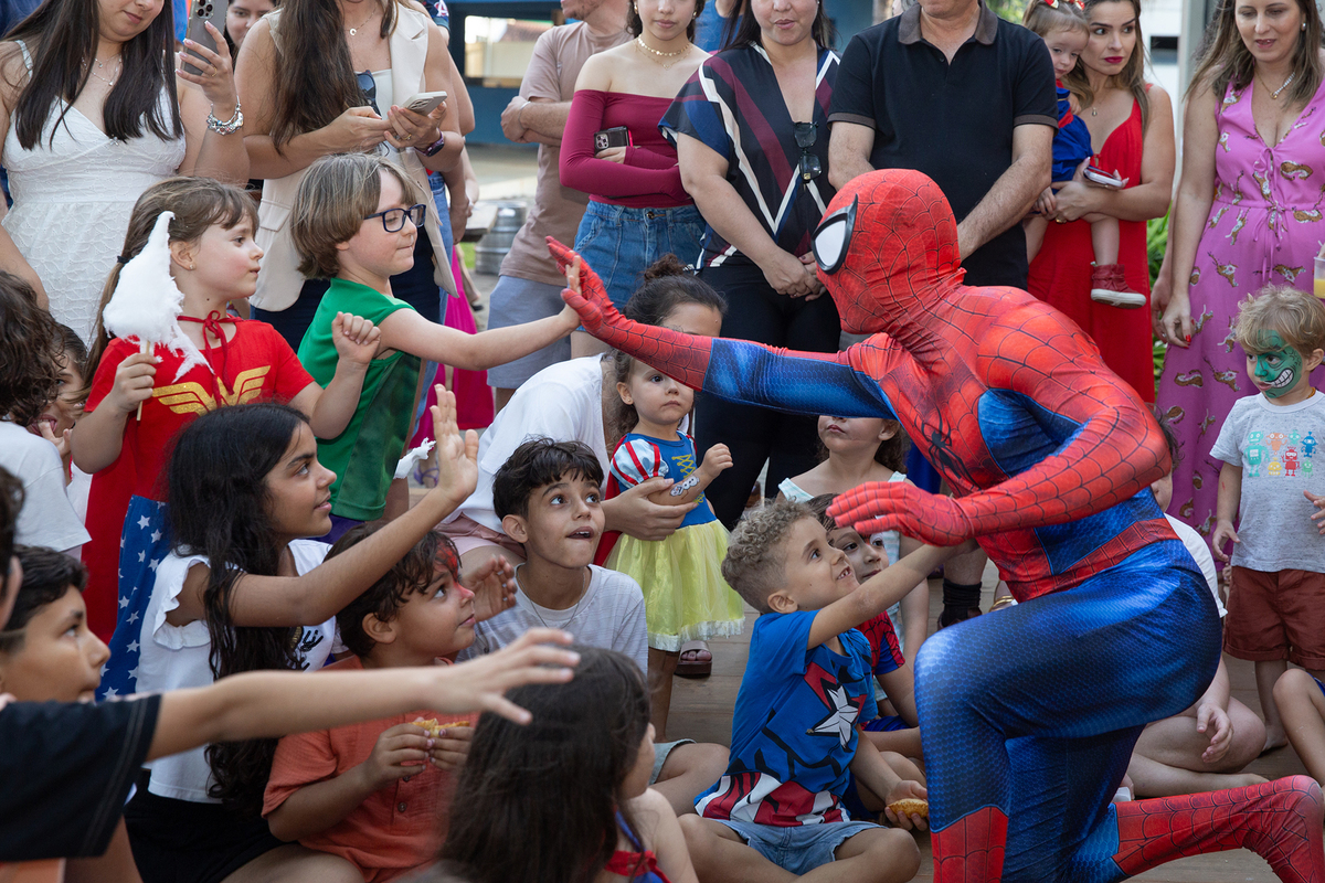 Momento de brincadeira entre crianças e o Homem-Aranha em festa infantil dos super heróis