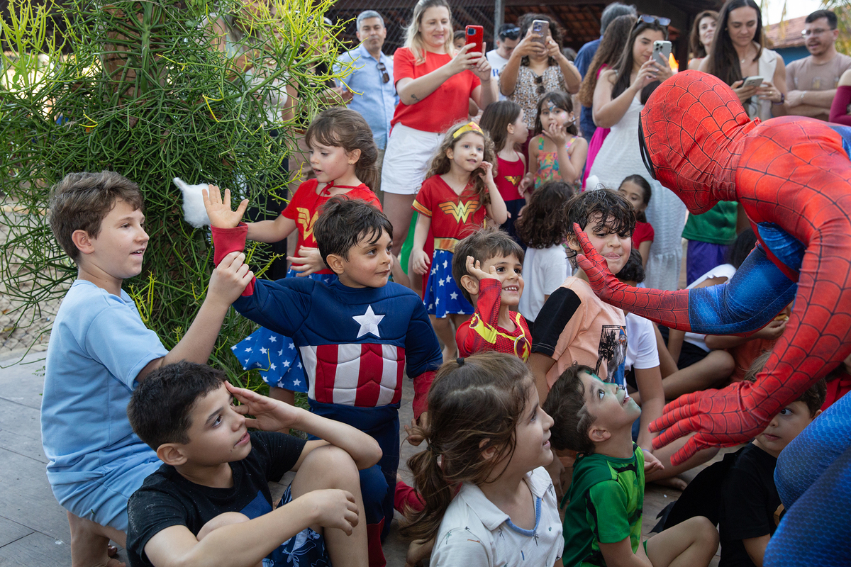 Momento de brincadeira entre crianças e o Homem-Aranha em festa infantil dos super heróis