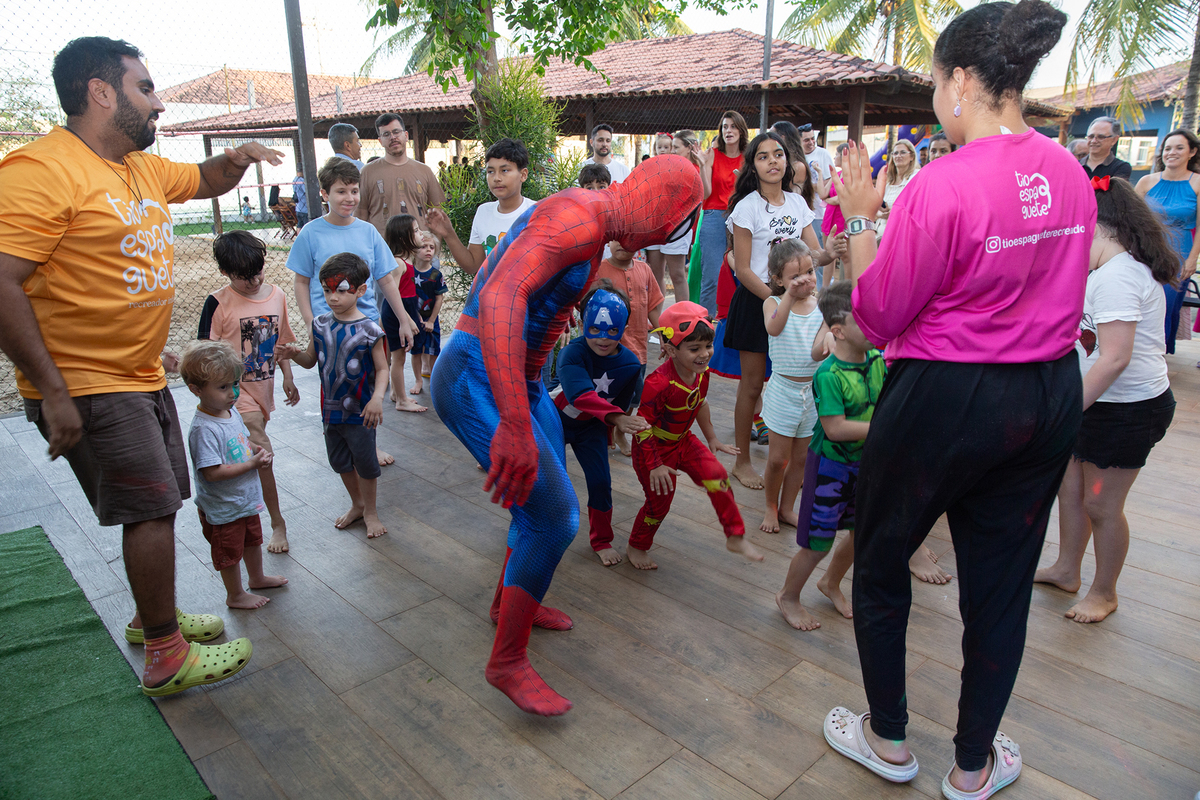 Momento de brincadeira entre crianças e o Homem-Aranha em festa infantil dos super heróis