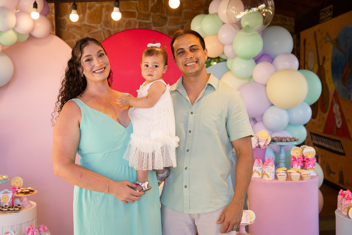 papai e mamãe brincando com aniversariante em frente a decoração 