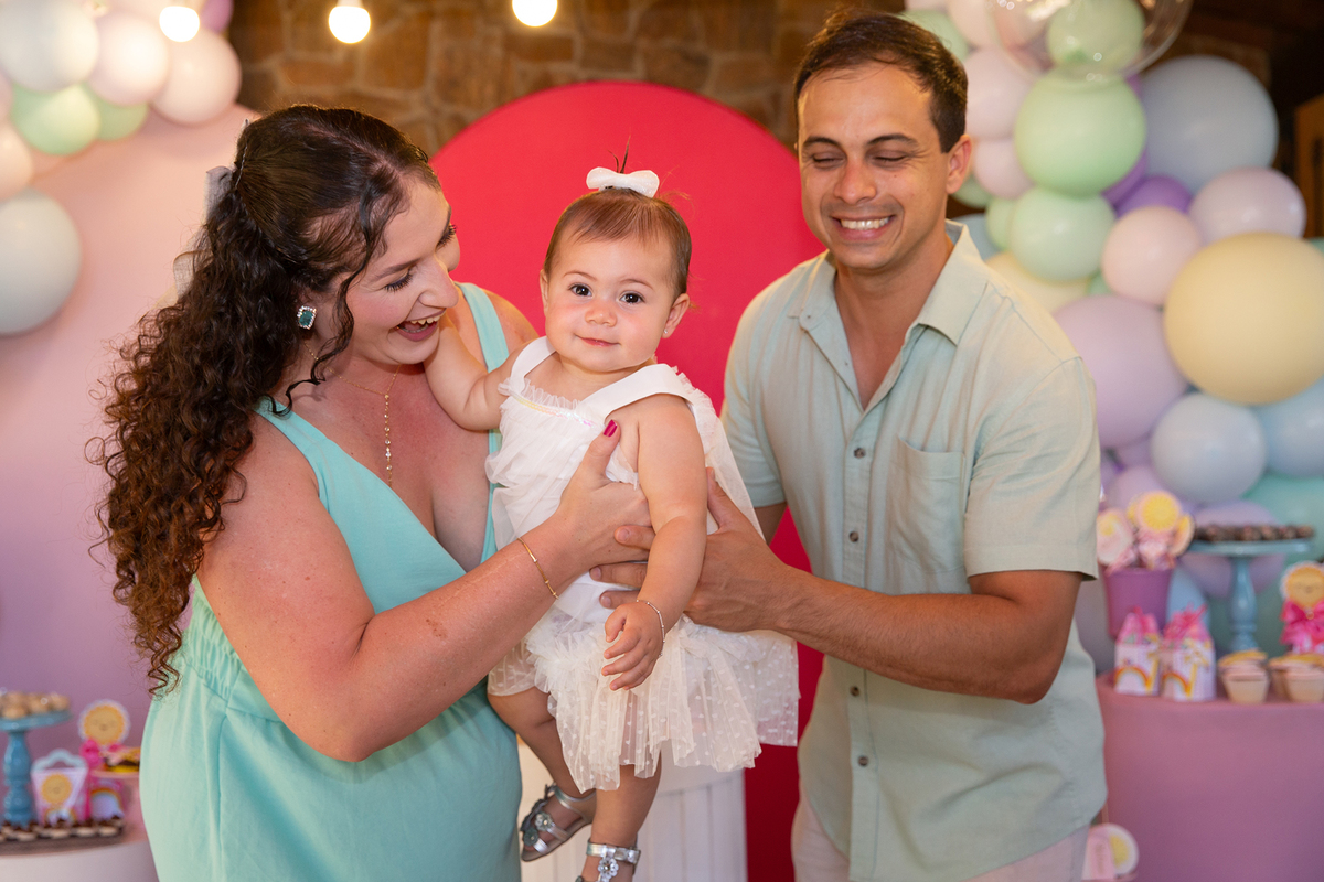 papai e mamãe brincando com aniversariante em frente a decoração 