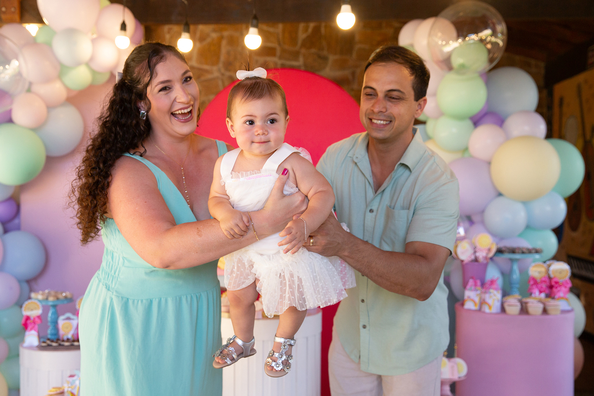 papai e mamãe brincando com aniversariante em frente a decoração 