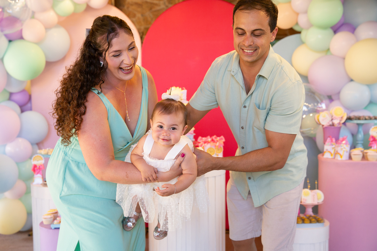 papai e mamãe brincando com aniversariante em frente a decoração 