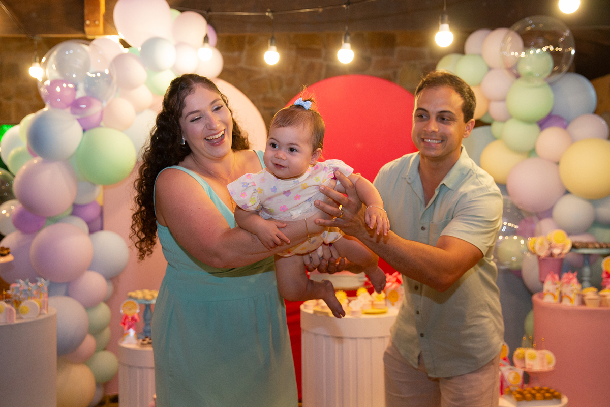 papai e mamãe brincando com aniversariante em frente a decoração na hora do parabéns 
