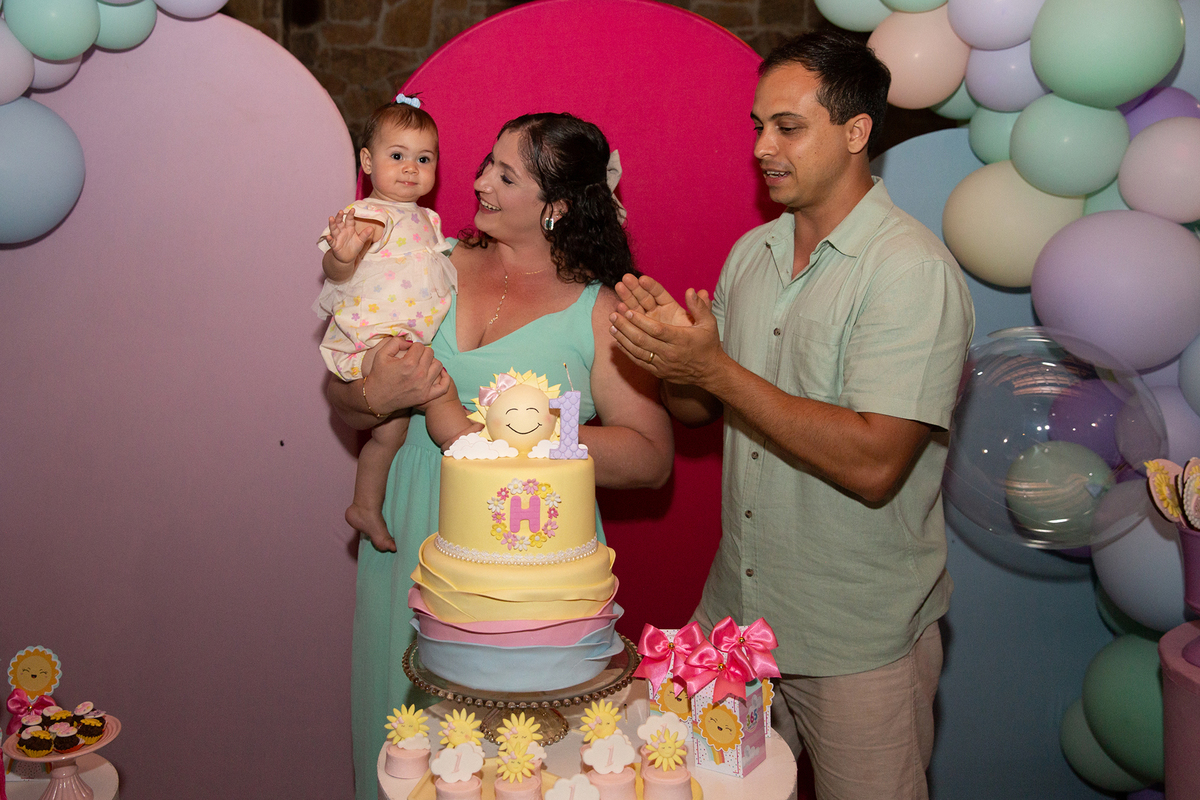papai, mamãe e aniversariante na mesa do bolo, durante o parabéns 