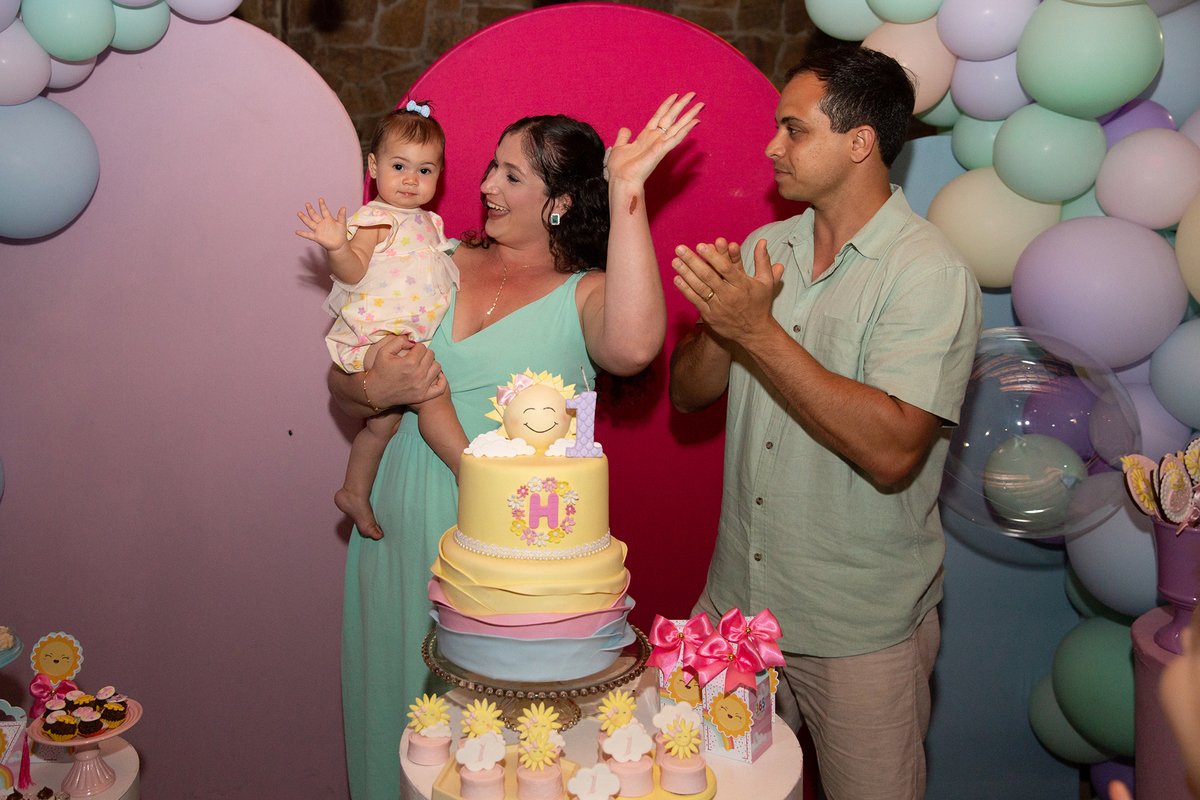 papai, mamãe e aniversariante na mesa do bolo, durante o parabéns 