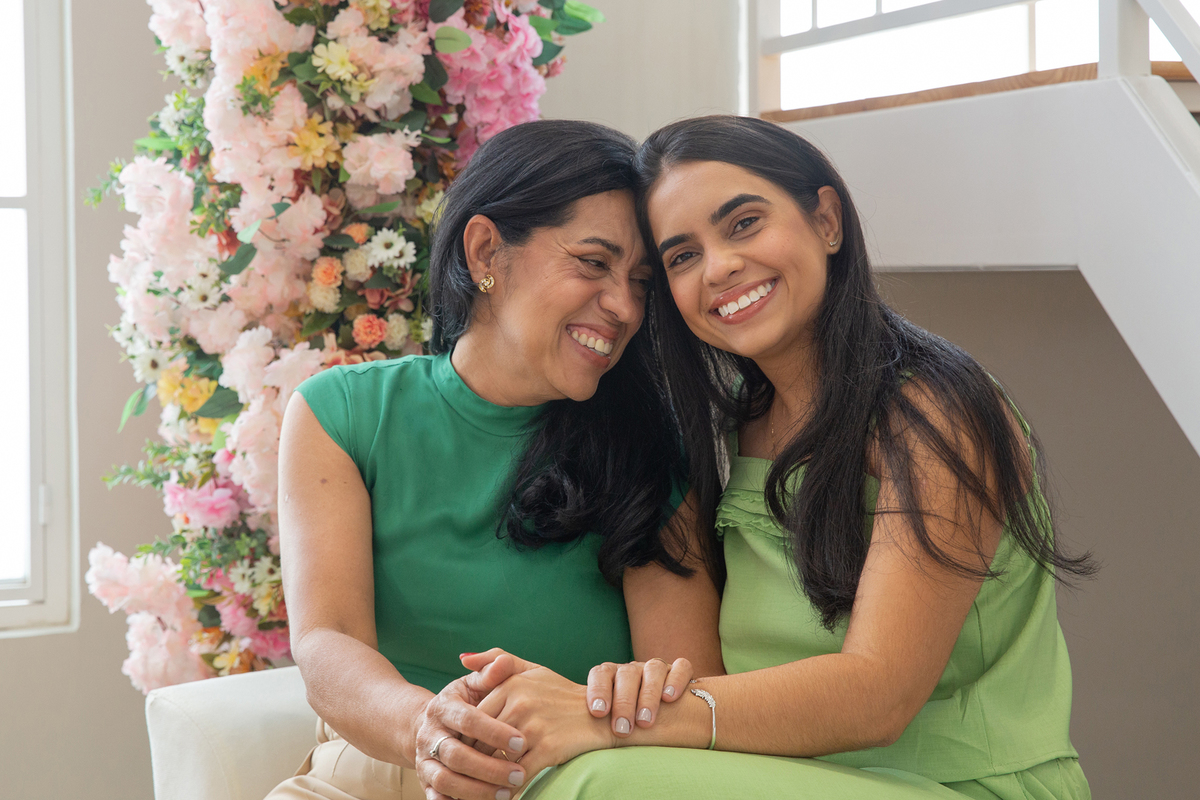 Mae e filha interagindo e sorrindo para foto juntas no cenário flores de dia das mães