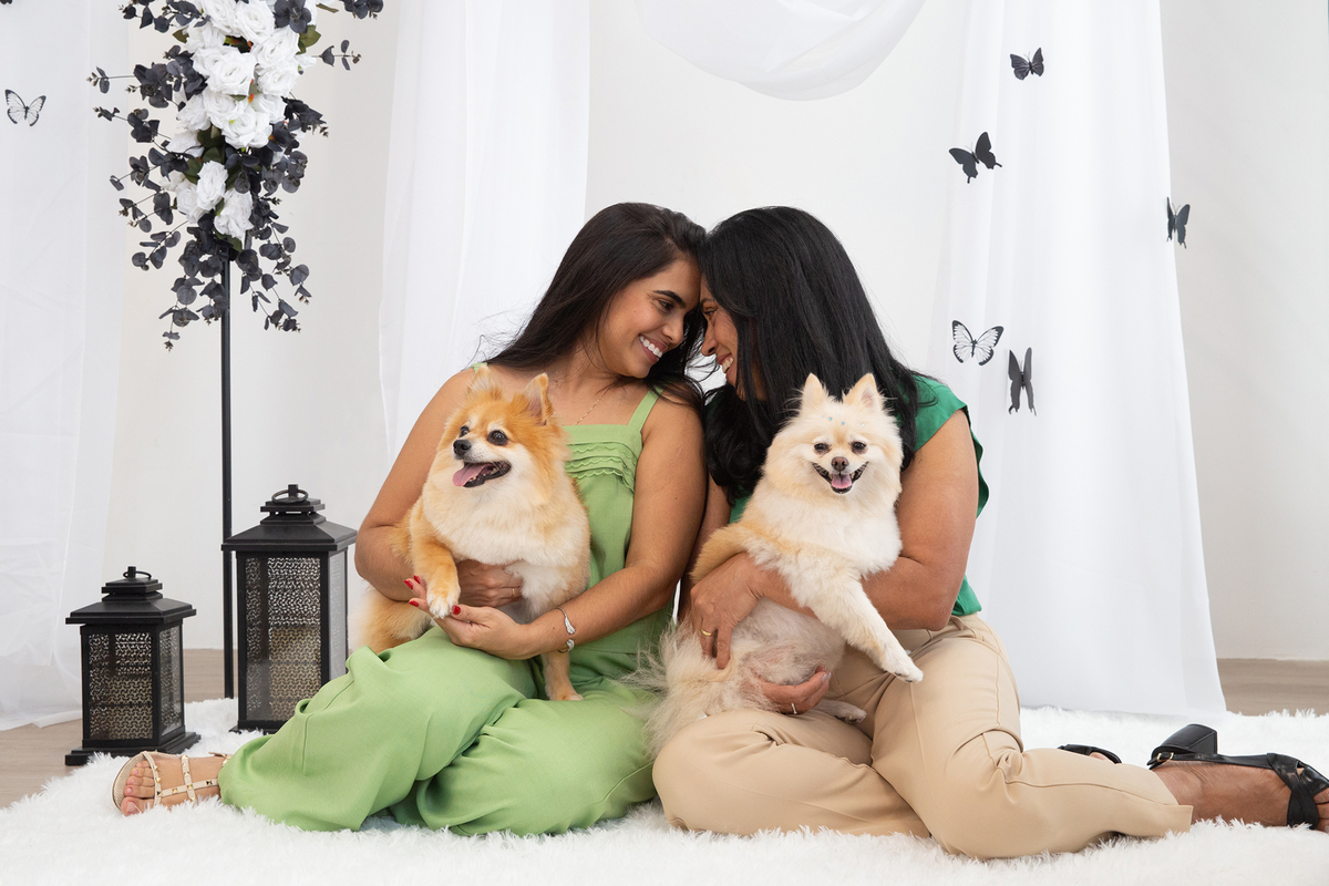 Os dois Spitz posando para foto juntos, no colo de mãe e filha, no cenário borboletas preto e branco 