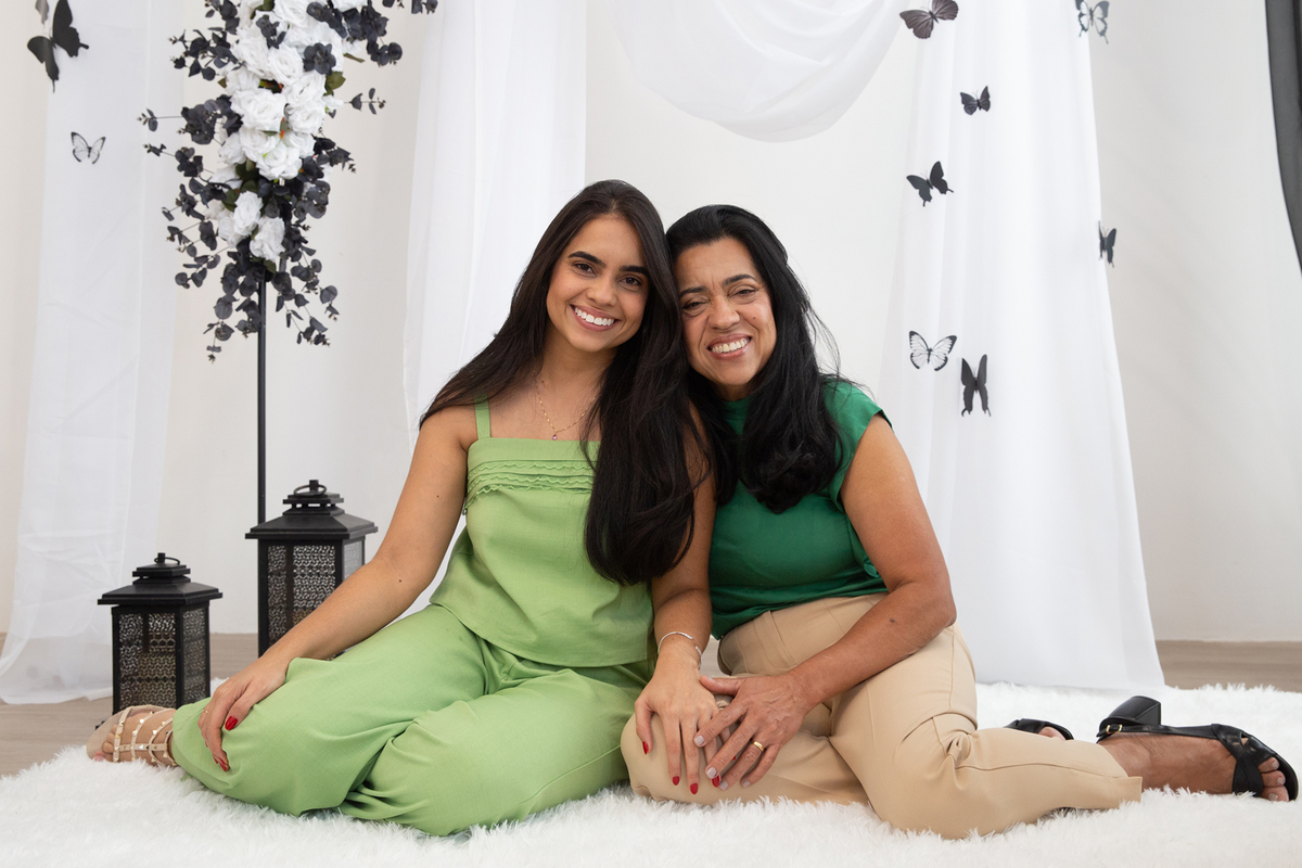 Mae e filha posando para foto juntas no cenário borboletas preto e branco