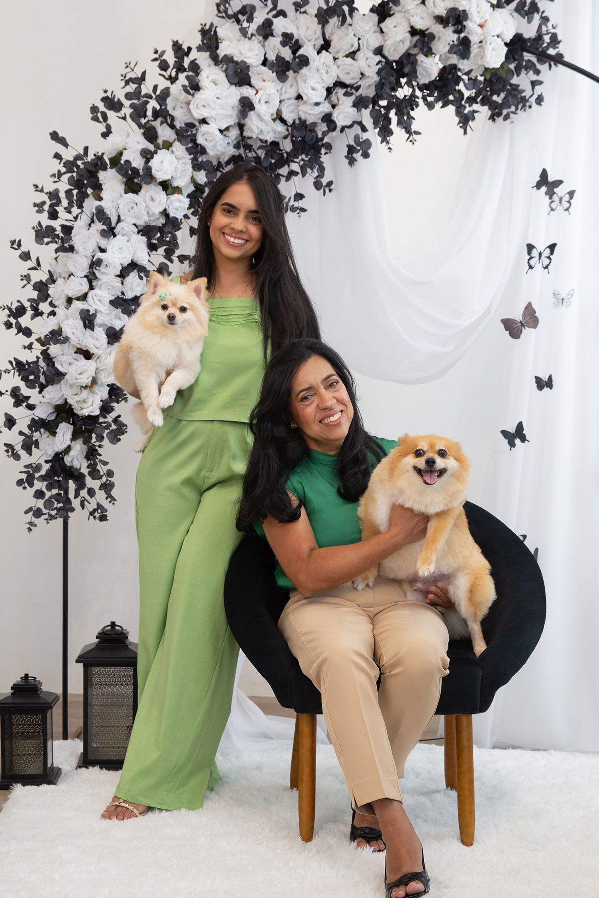 Os dois Spitz posando para foto juntos, no colo de mãe e filha, no cenário borboletas preto e branco 
