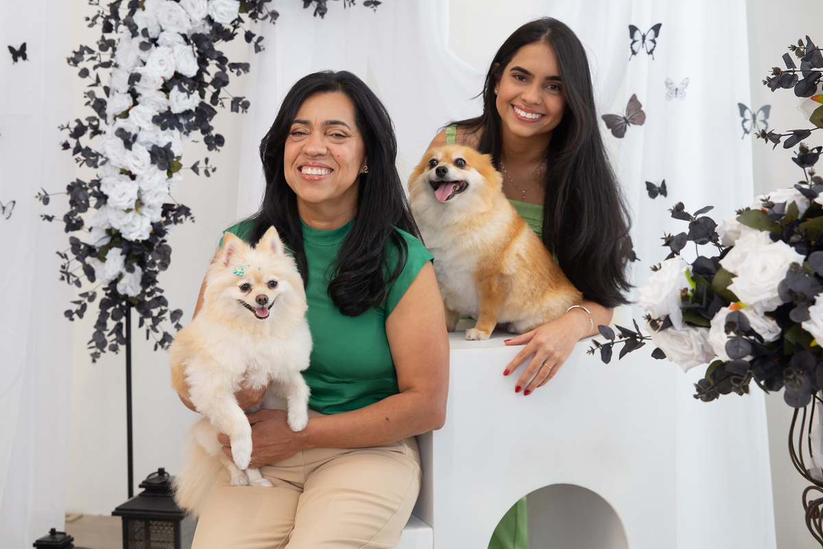 Os dois Spitz posando para foto juntos, no colo de mãe e filha, no cenário borboletas preto e branco 