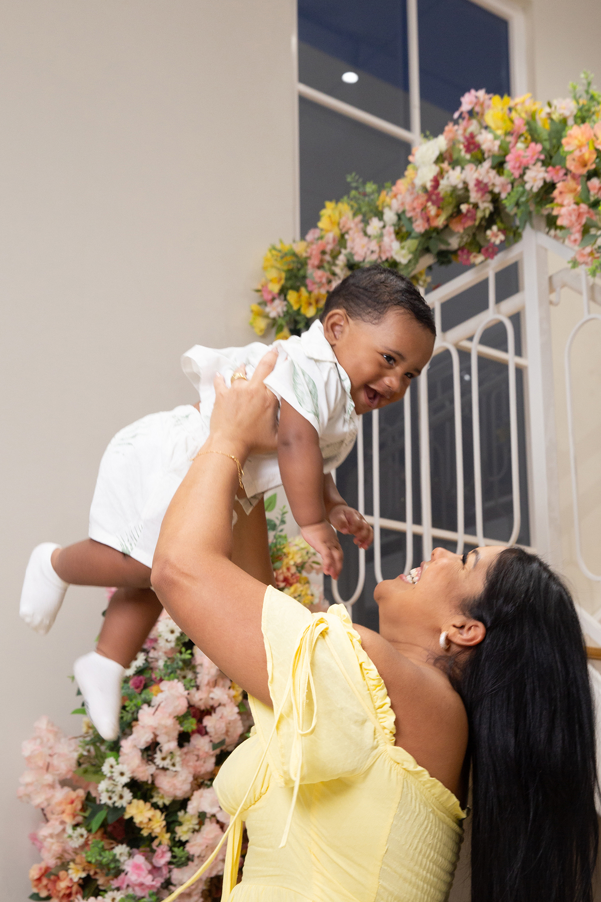 mãe e filho interagindo, brincando no cenário de dia das mães Flores, os dois sorrindo