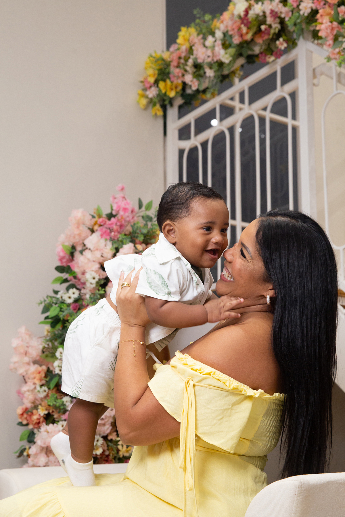 mãe e filho interagindo, brincando no cenário de dia das mães Flores, os dois sorrindo