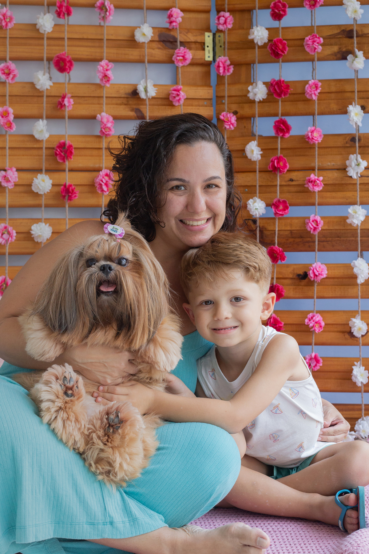 Shih-tzu posando para câmera no cenário, junto com sua mãe e irmão humanas