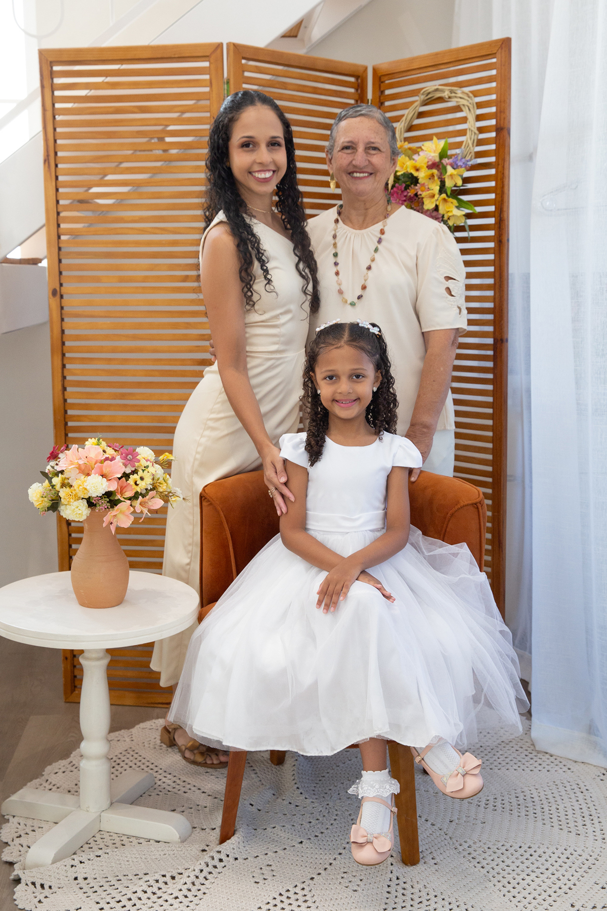 Mãe, filha e avó, sorriem para câmera, no cenário flores do dia das mães