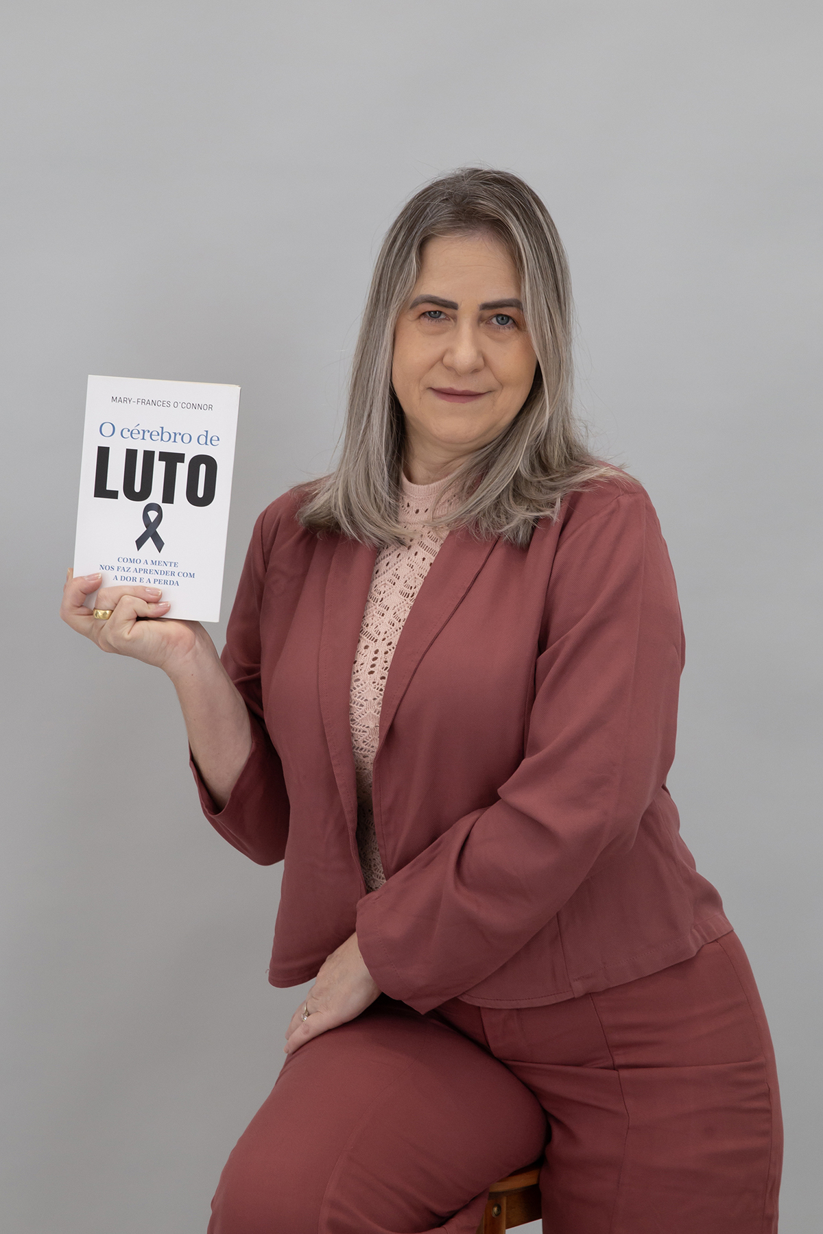 Maristela, psicóloga, segurando um livro sobre luto em retrato profissional