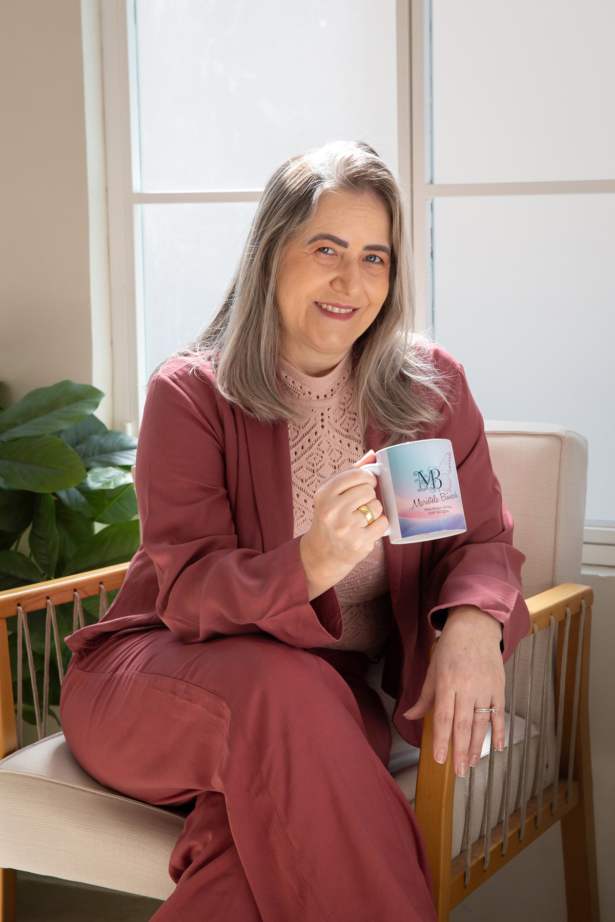 Psicóloga Maristela segurando uma caneca personalizada em ambiente acolhedor