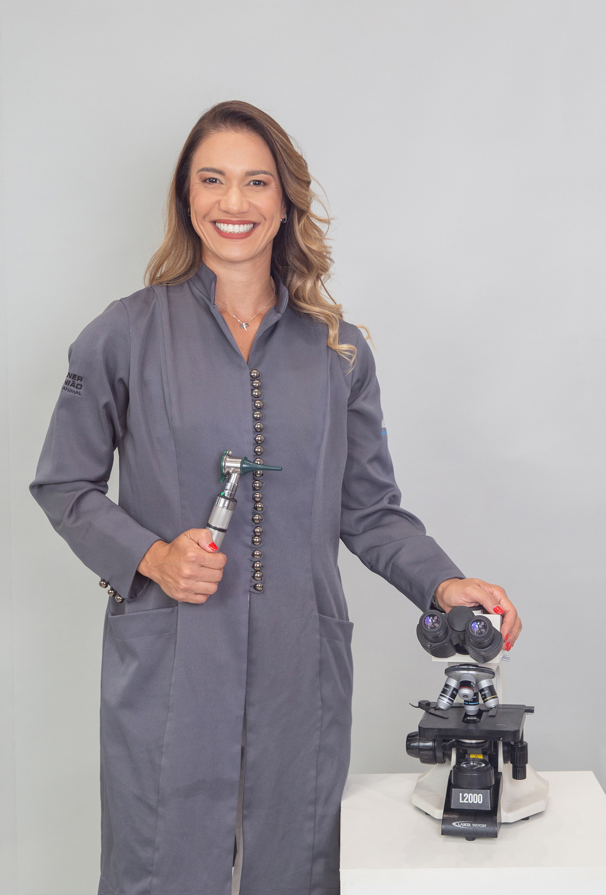 Veterinária dermatologista Aline Galante em retrato profissional com equipamento de laboratório.