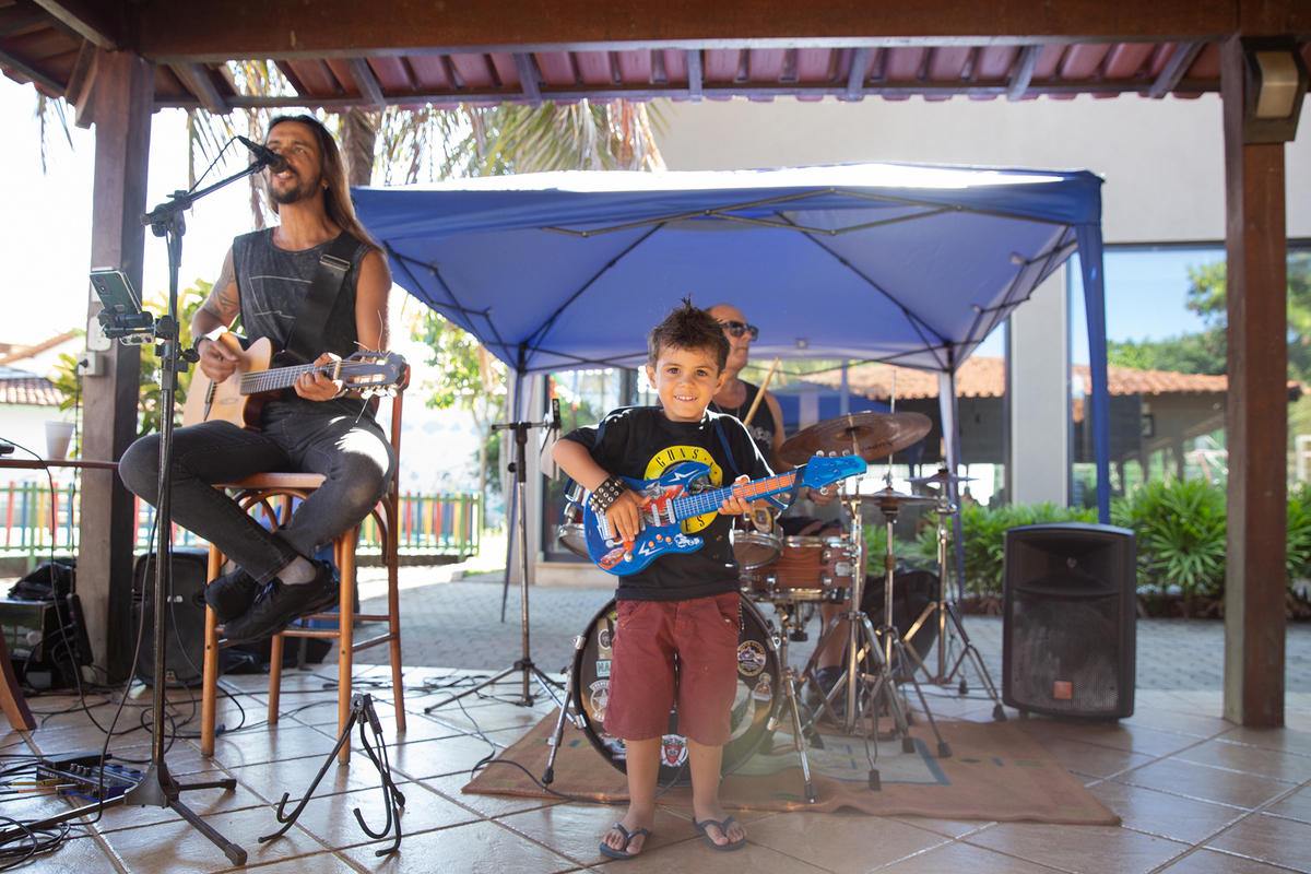 Aniversariante tocando guitarra de brinquedo com a banda.