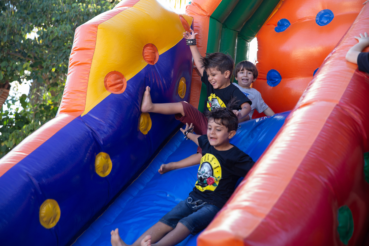 Crianças se divertindo no escorregador inflável da festa.