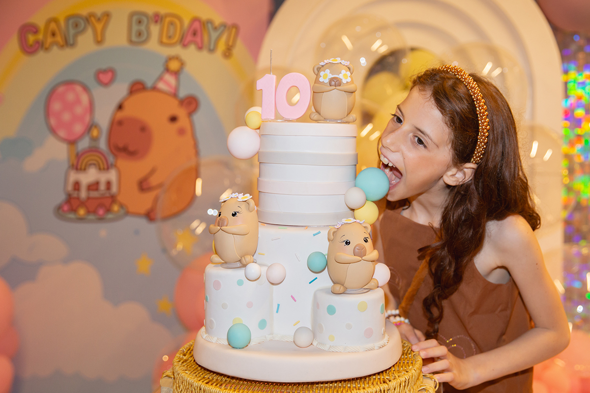 Clara ao lado do bolo personalizado de aniversário.
