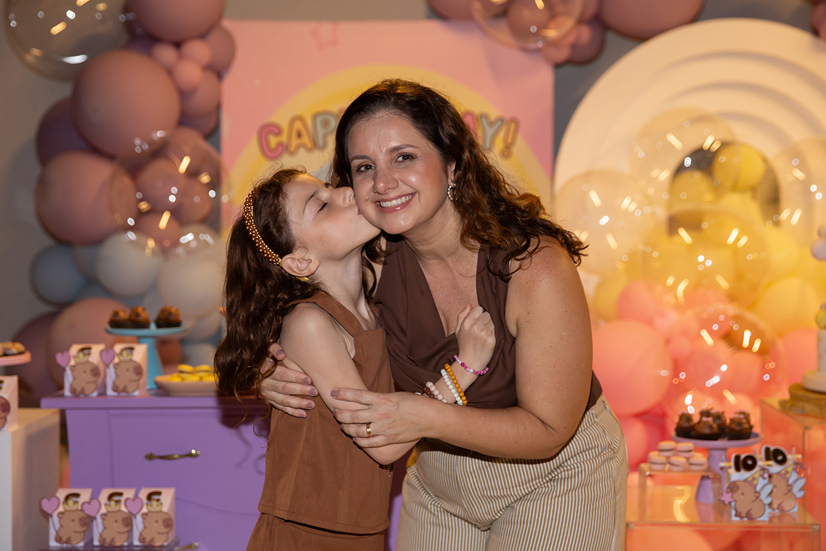 Abraço carinhoso entre Clara e a mãe durante a festa.