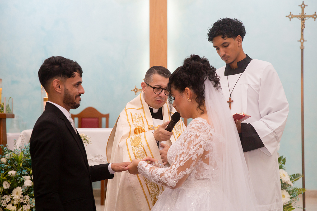 Troca de alianças diante do altar durante o casamento religioso.