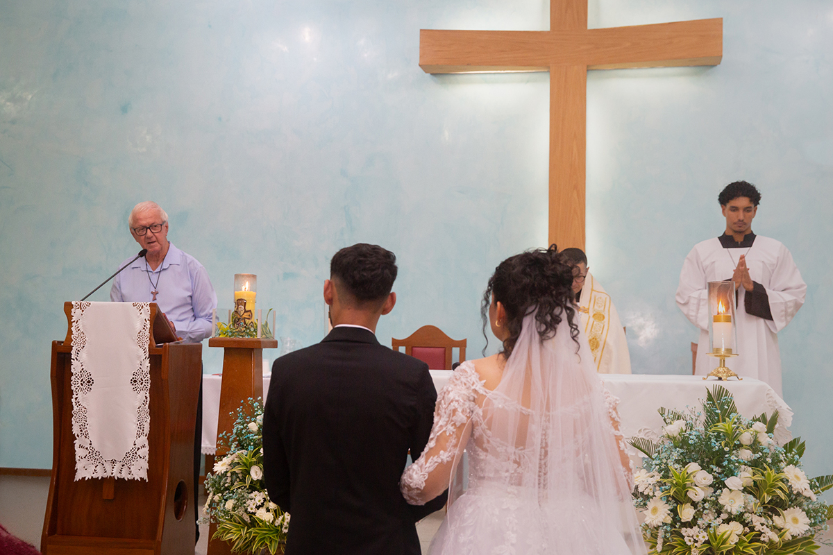 Casal diante do altar recebendo a bênção matrimonial.