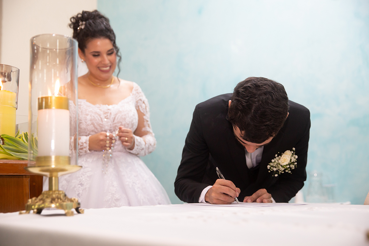 Noivo assinando os documentos da cerimônia religiosa.