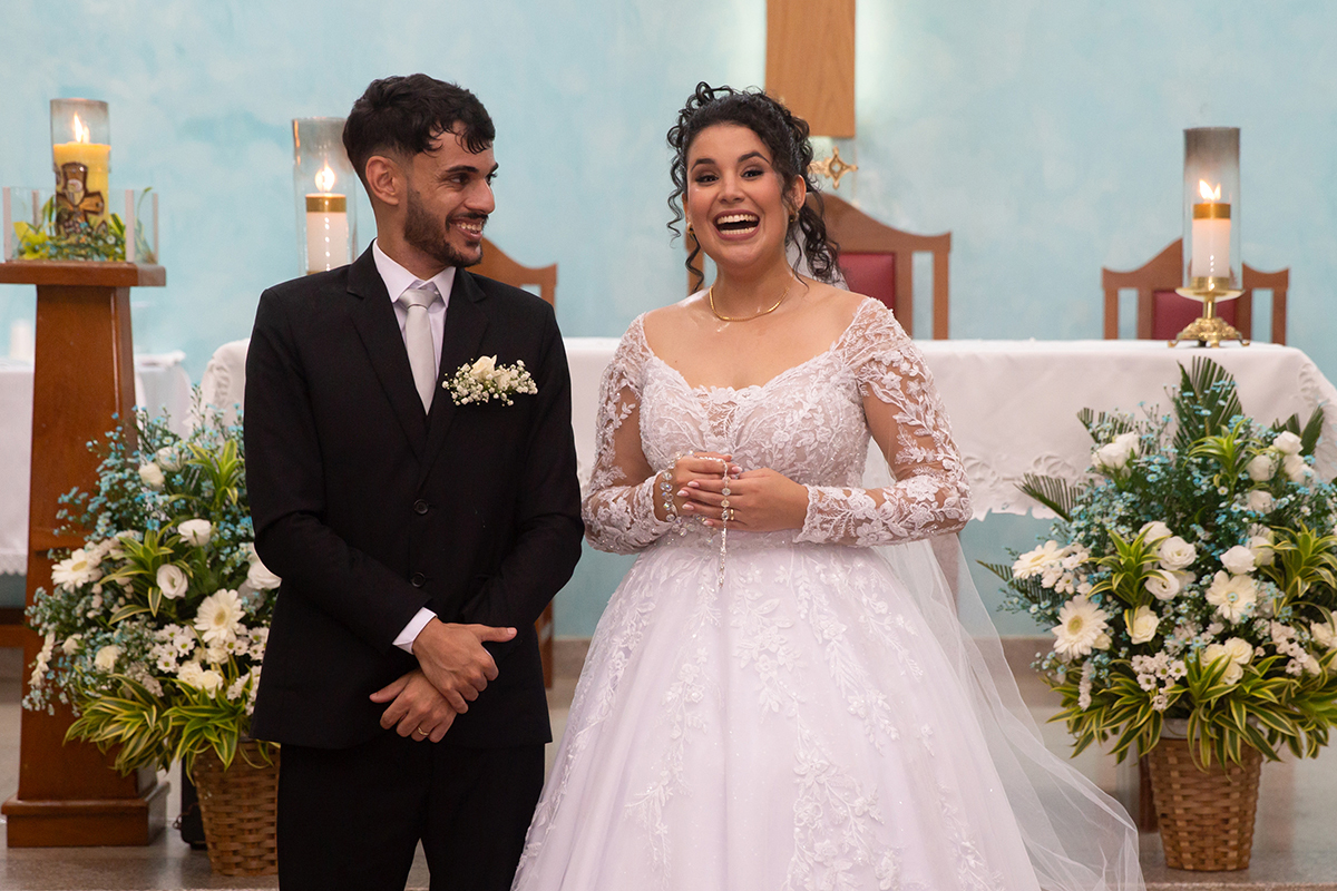 Ester e Renan sorrindo no altar após a celebração do casamento religioso.