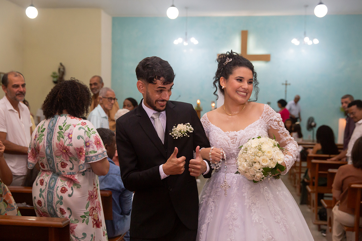 Noivos caminhando felizes pelo corredor da igreja após a cerimônia.