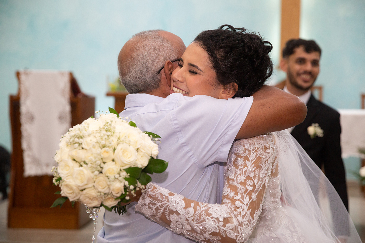 Abraço emocionante dos noivos após a cerimônia religiosa na igreja.