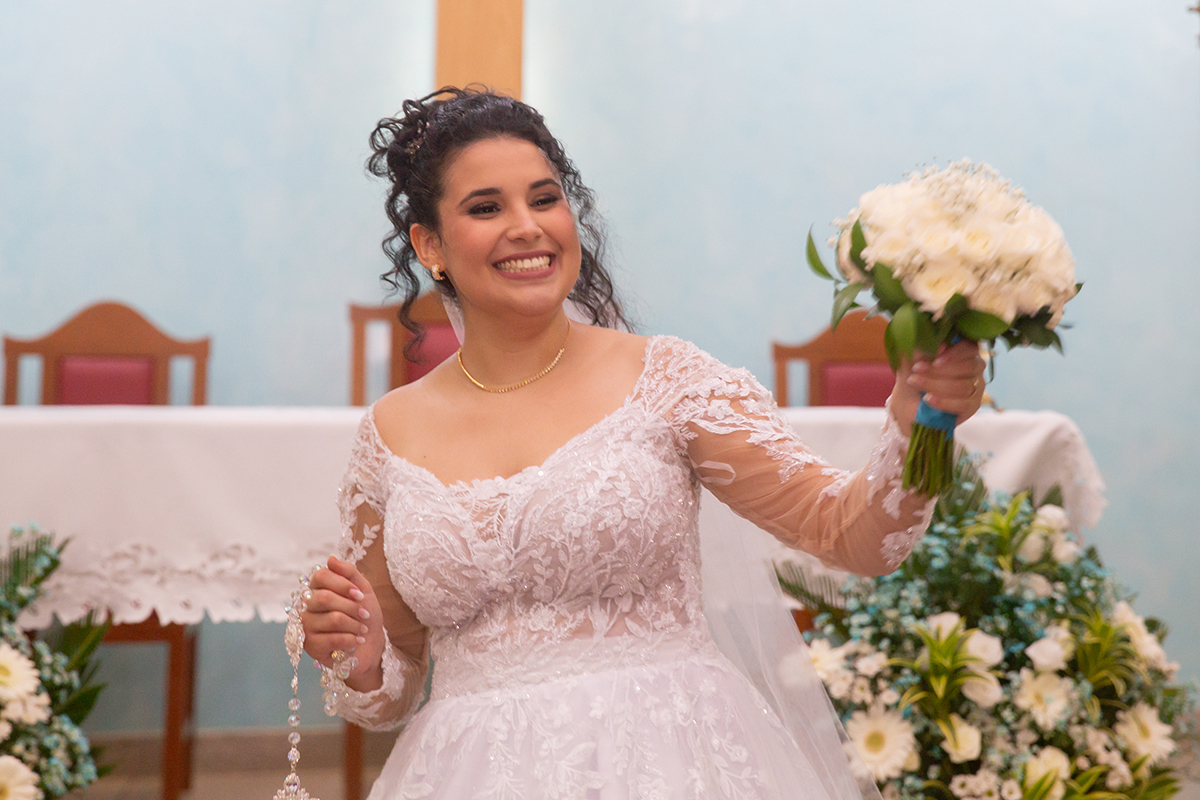 Noiva Ester celebrando o casamento religioso com o buquê em mãos.