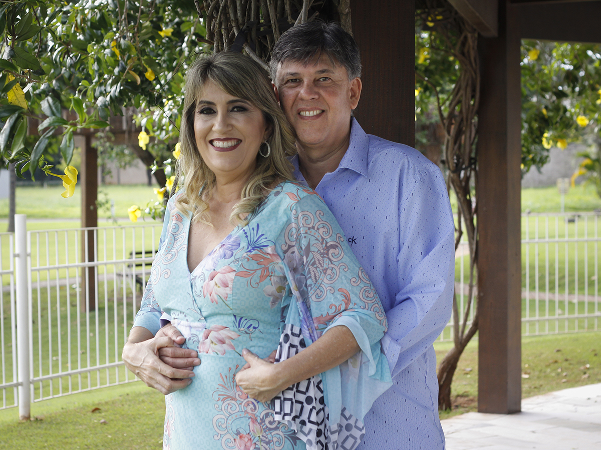 Casal posa em dia ensolarado, na beira da piscina