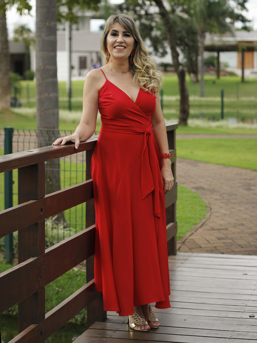 Mãe apoiada no corrimão da ponte olha para câmera, mostrando o vestido