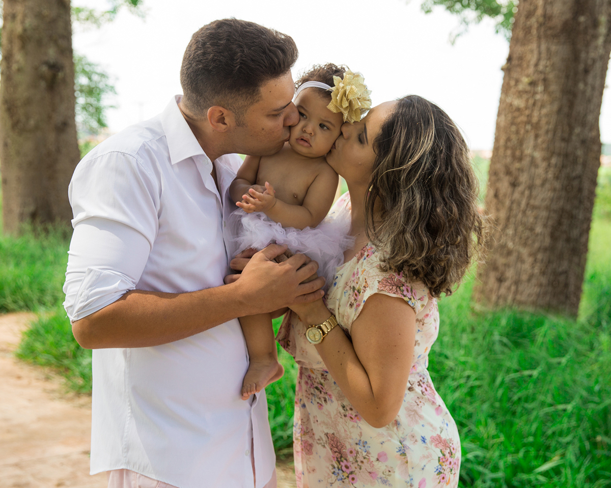 Papai e mamãe beijam bebê ao mesmo tempo, um de cada lado das bochechas