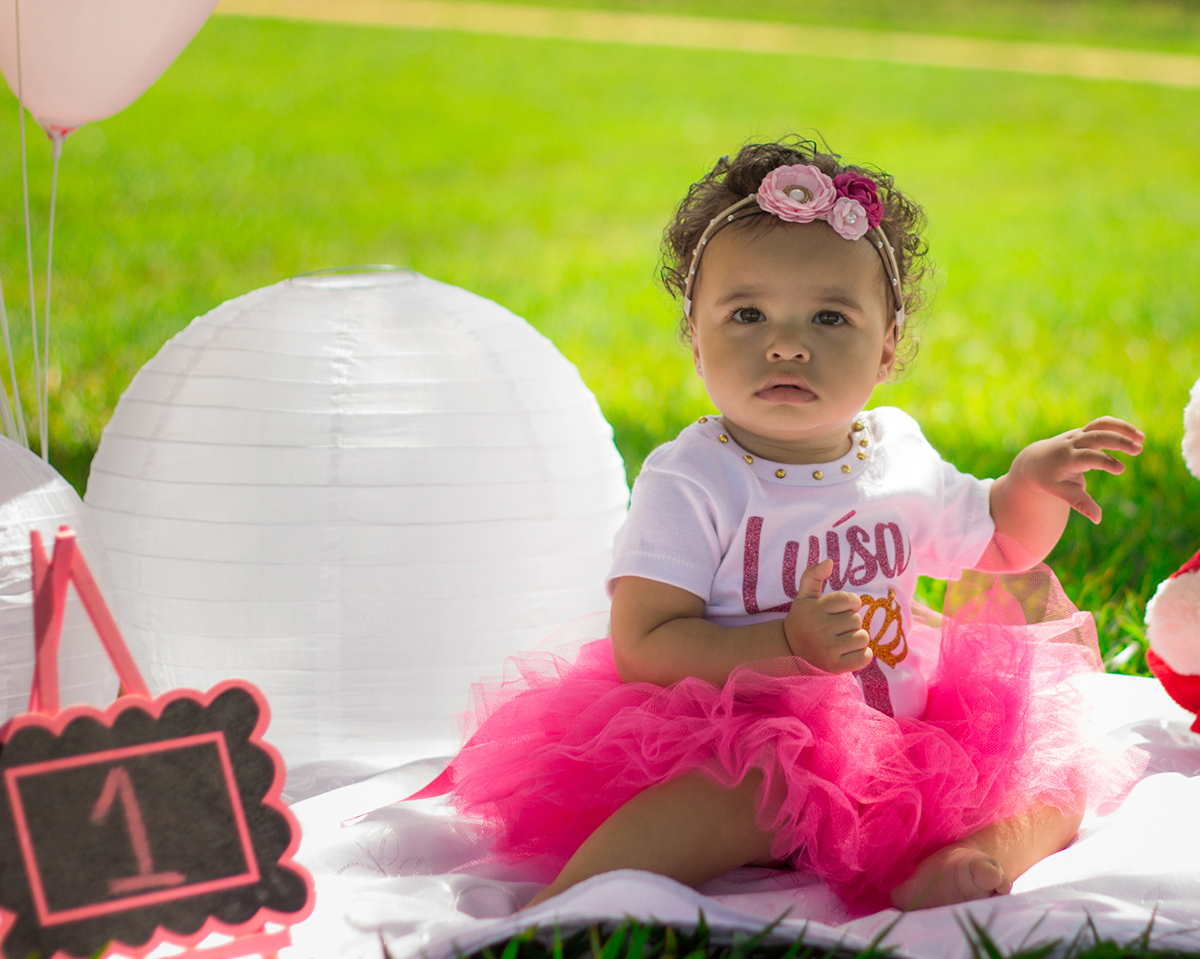 Bebê sentada no cenário, com saia de tutu e body personalizado